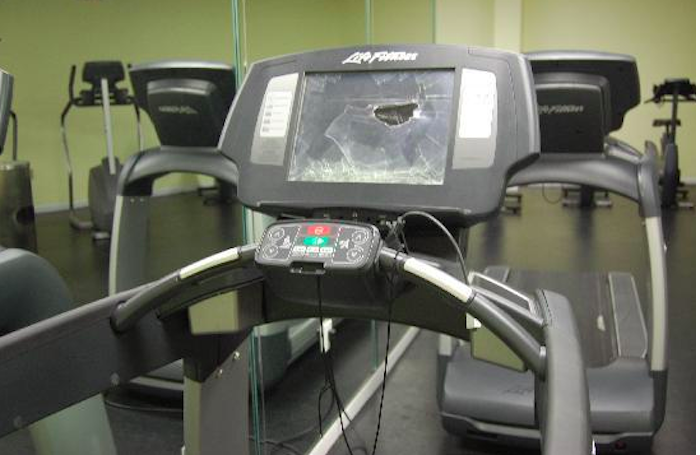 Broken treadmill screen in a gym, likely needing disposal services.